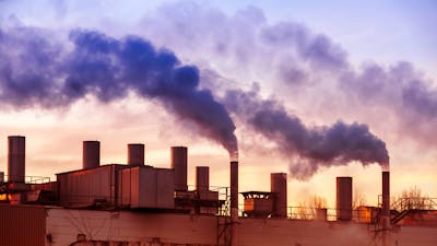 Dark smoke comming from the chimneys of an old factory.