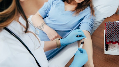 cropped view of donor and doctor with syringe obtaining blood sample