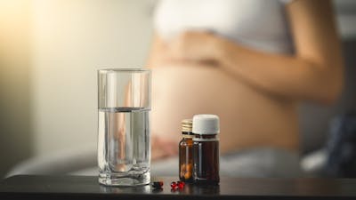 Conceptual photo of pregnancy healthcare. Closeup photo of medicines on table next to pregnant woman