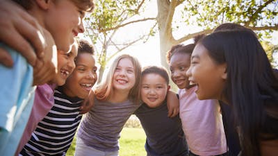 Group of schoolchildren embrace standing in a circle